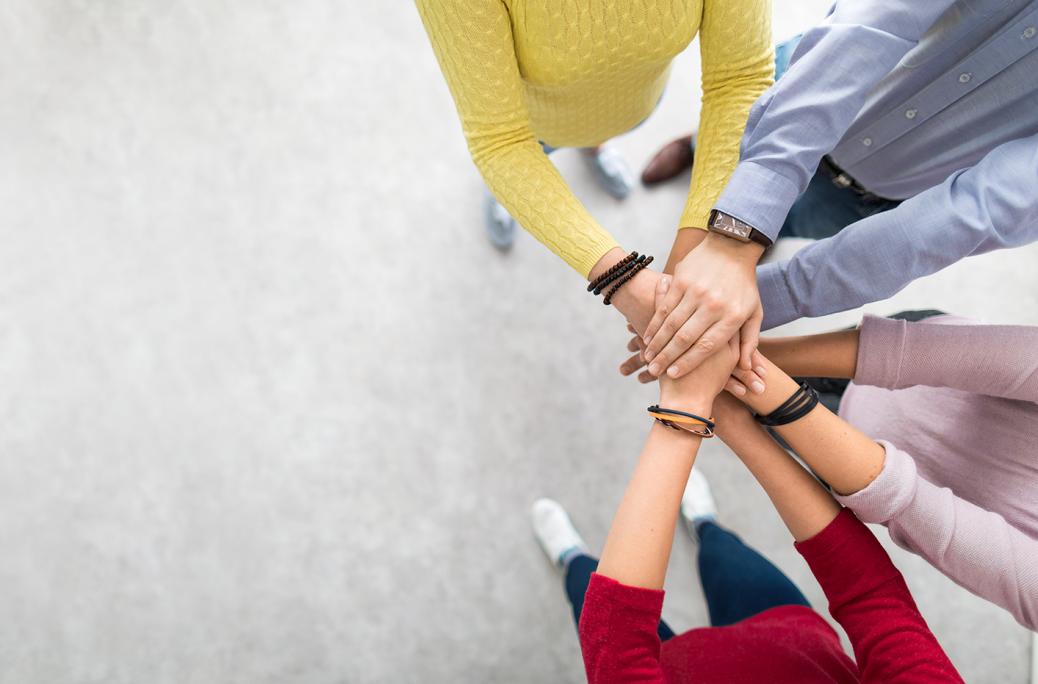 Team members placing hands on top of hands