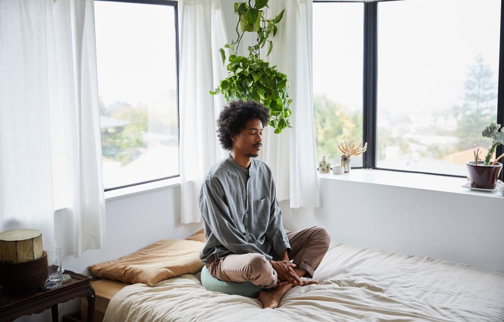 Man sitting on bed meditating 