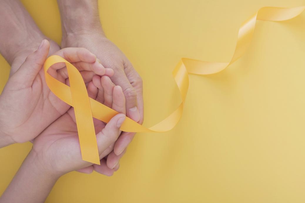 Two pairs of hands cupling a yellow ribbon