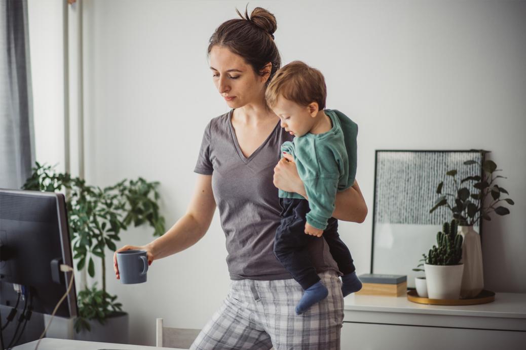 Woman holding her baby while getting ready to log onto her computer