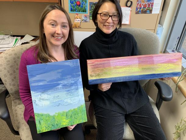 Photo of Donna Power and Lisa Murata holding paintings Photo of Donna Power and Lisa Murata holding paintings