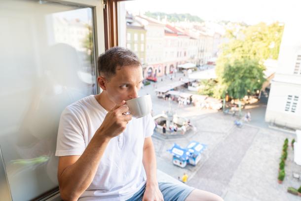 Man sipping on coffee by an open window