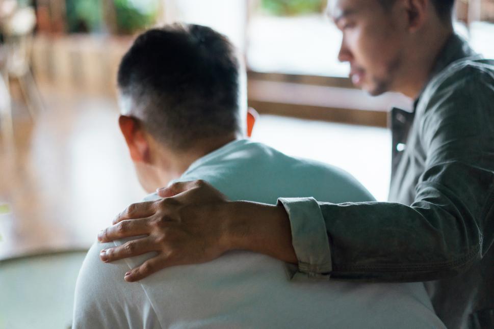 Man consoling other man with hand on shoulder