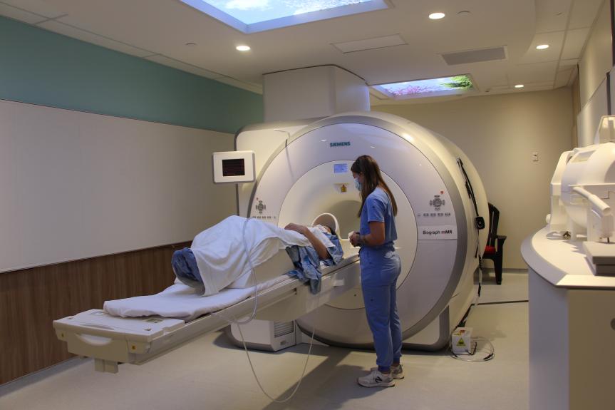Person lying in the MRI machine with researcher by their side