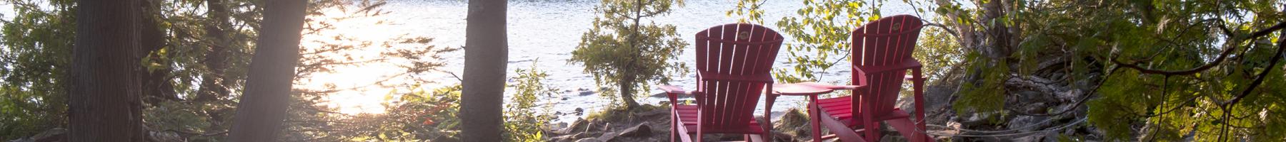 Peaceful setting in the woods with two empty chairs looking onto to lake