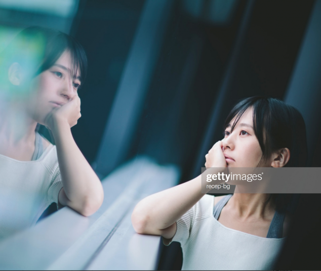 Woman looking at her reflection in a window