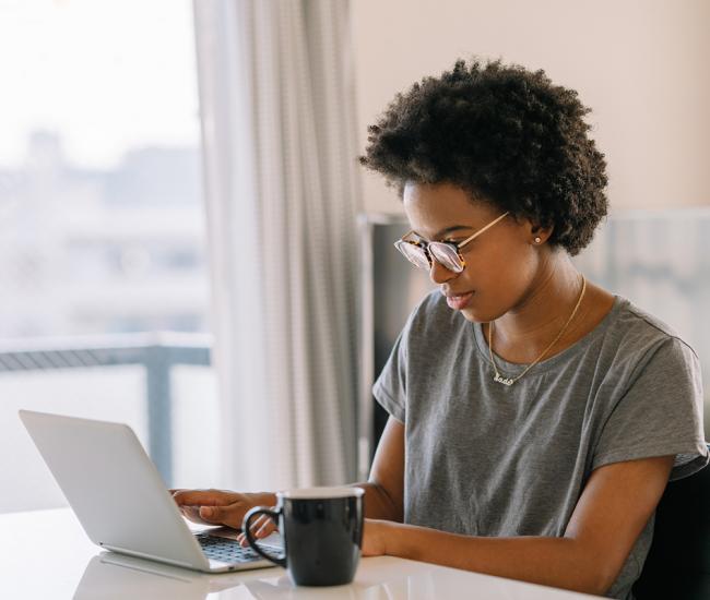 Woman sitting down at table and typing on a laptop