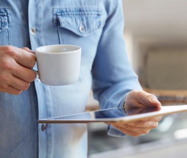 Man with coffee reading from his tablet