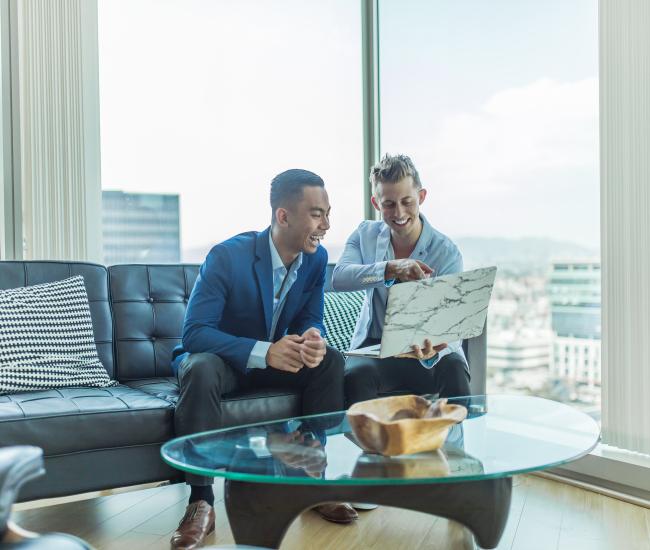 Two men sitting on a couch looking at laptop