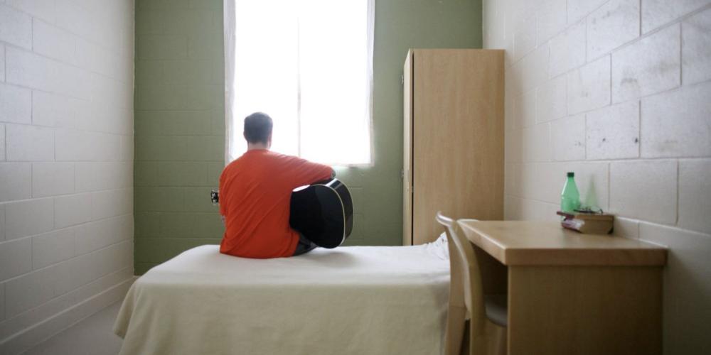 Un patient joue de la guitare alors qu'il est assis sur son lit dans la chambre