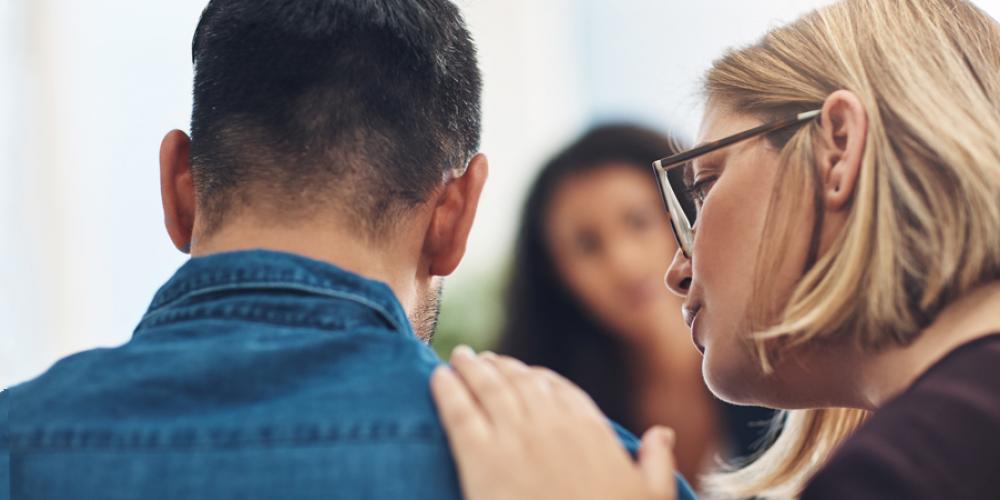 Woman offering comfort with hand on man's shoulder