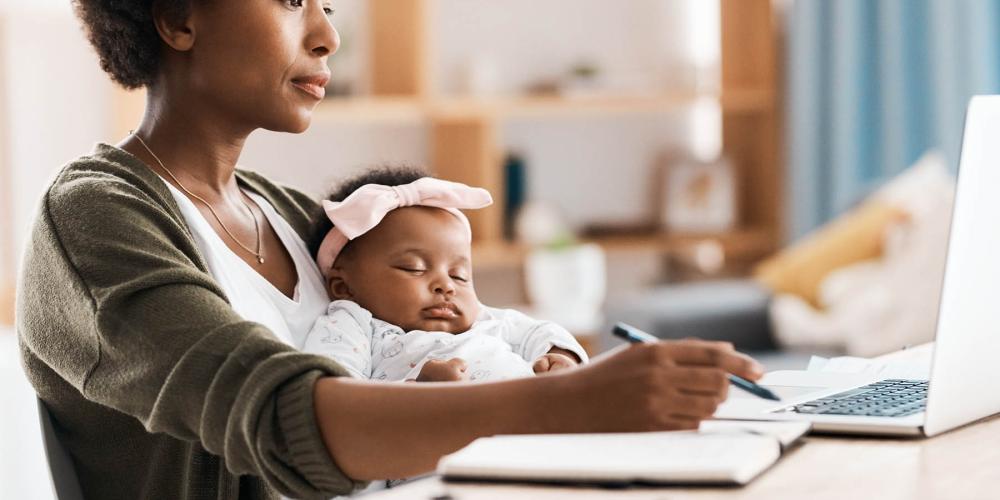 Une maman écrit dans son journal avec son bébé sur les genoux.