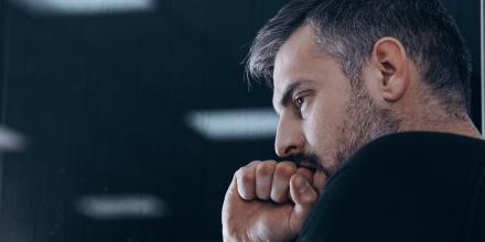 Man biting his finger on clenched fist hand