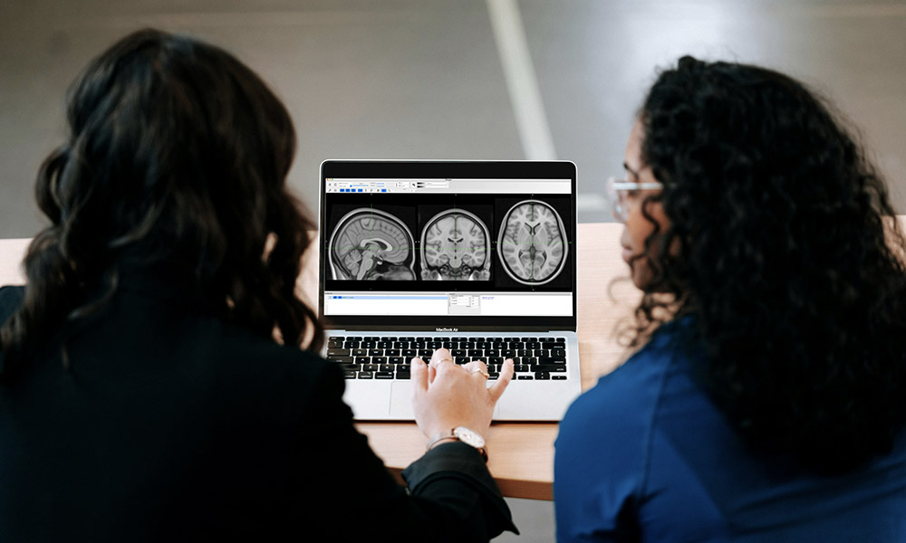 Two doctors look over brain scans on a laptop