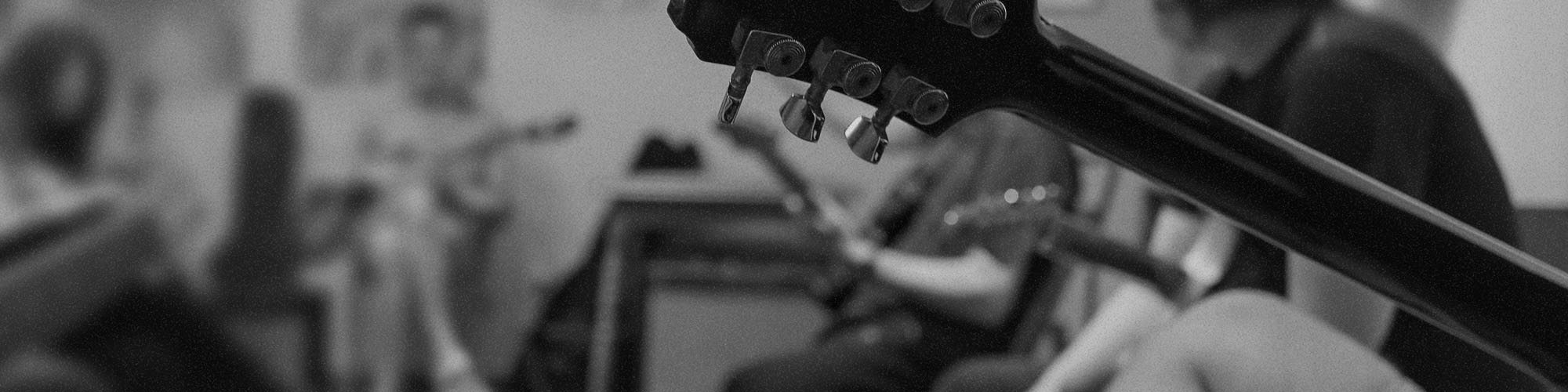 Black and white photo of a music therapy session, with a guitar in the foreground.