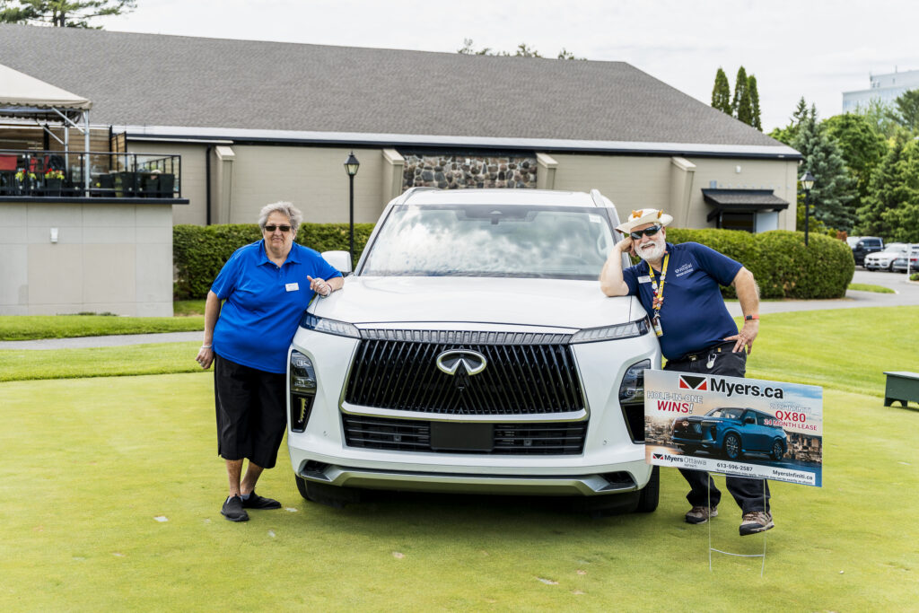 Volunteers pose with a car at the Royal Open Golf Tournament